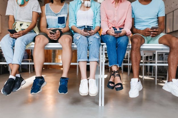 young-man-blue-sneakers-spending-time-with-friends-typing-new-message-his-cell-indoor-portrait-students-sitting-together-desk-using-smartphones_197531-3843